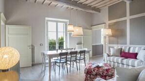Uma área de refeições com mesa, cadeiras, um sofá e um abajur.