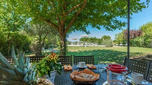 Uma área de refeições ao ar livre com uma mesa posta para dois, rodeada por vegetação e vista para a paisagem.