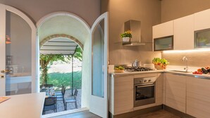 Uma cozinha moderna com um arco que dá para uma área de refeições ao ar livre, fogão embutido e micro-ondas.
