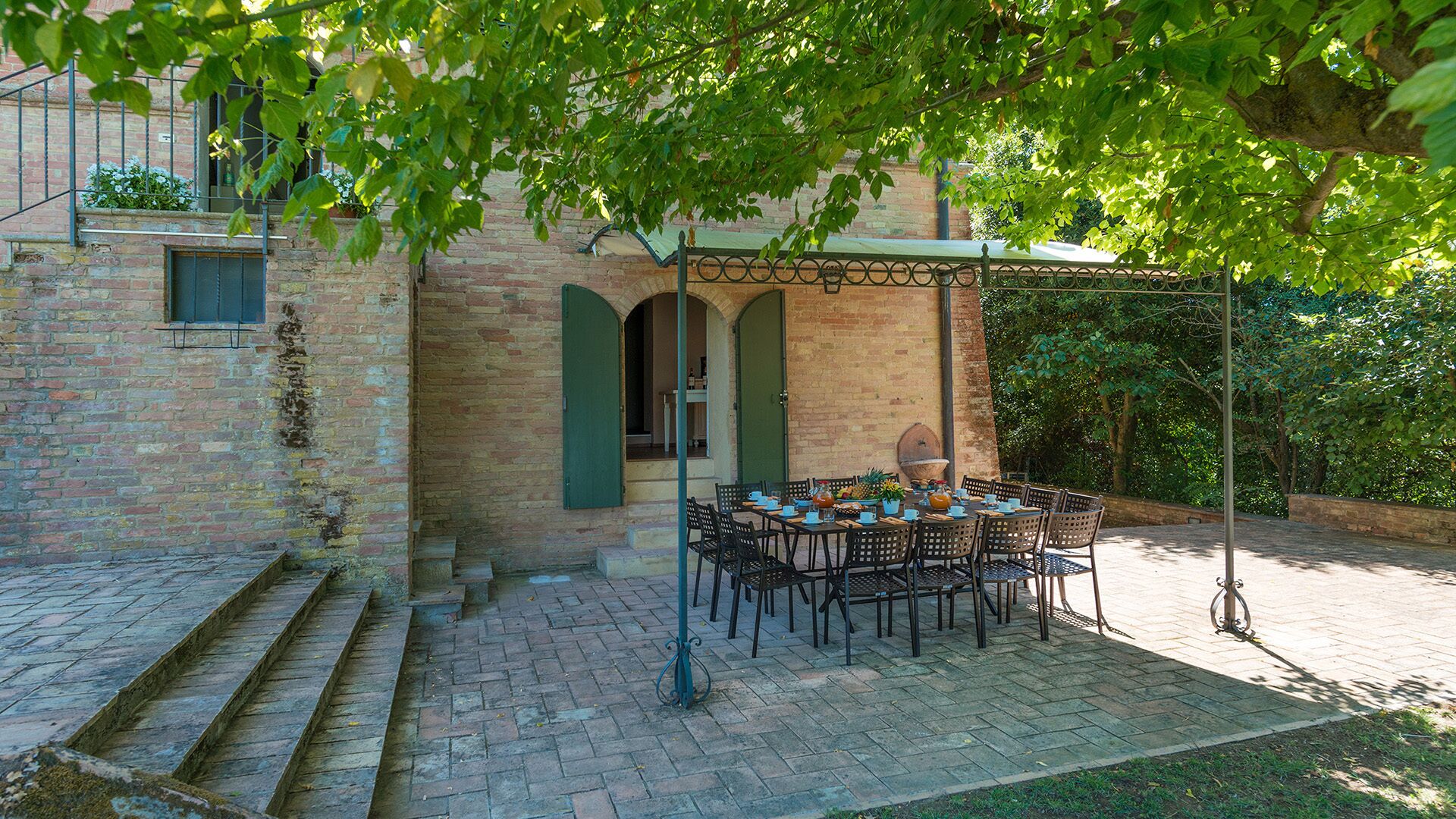 A patio area with a table set for dining, surrounded by brick walls and a covered seating area.