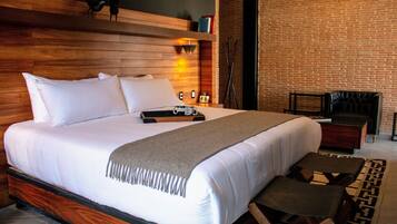Una habitación de hotel moderna con una cama grande, cabecero de madera y una pared de ladrillo.