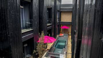 Un edificio moderno con un patio estrecho, piscina y plantas en macetas.