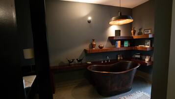 Un baño moderno con una bañera independiente, estantes de madera y objetos decorativos.