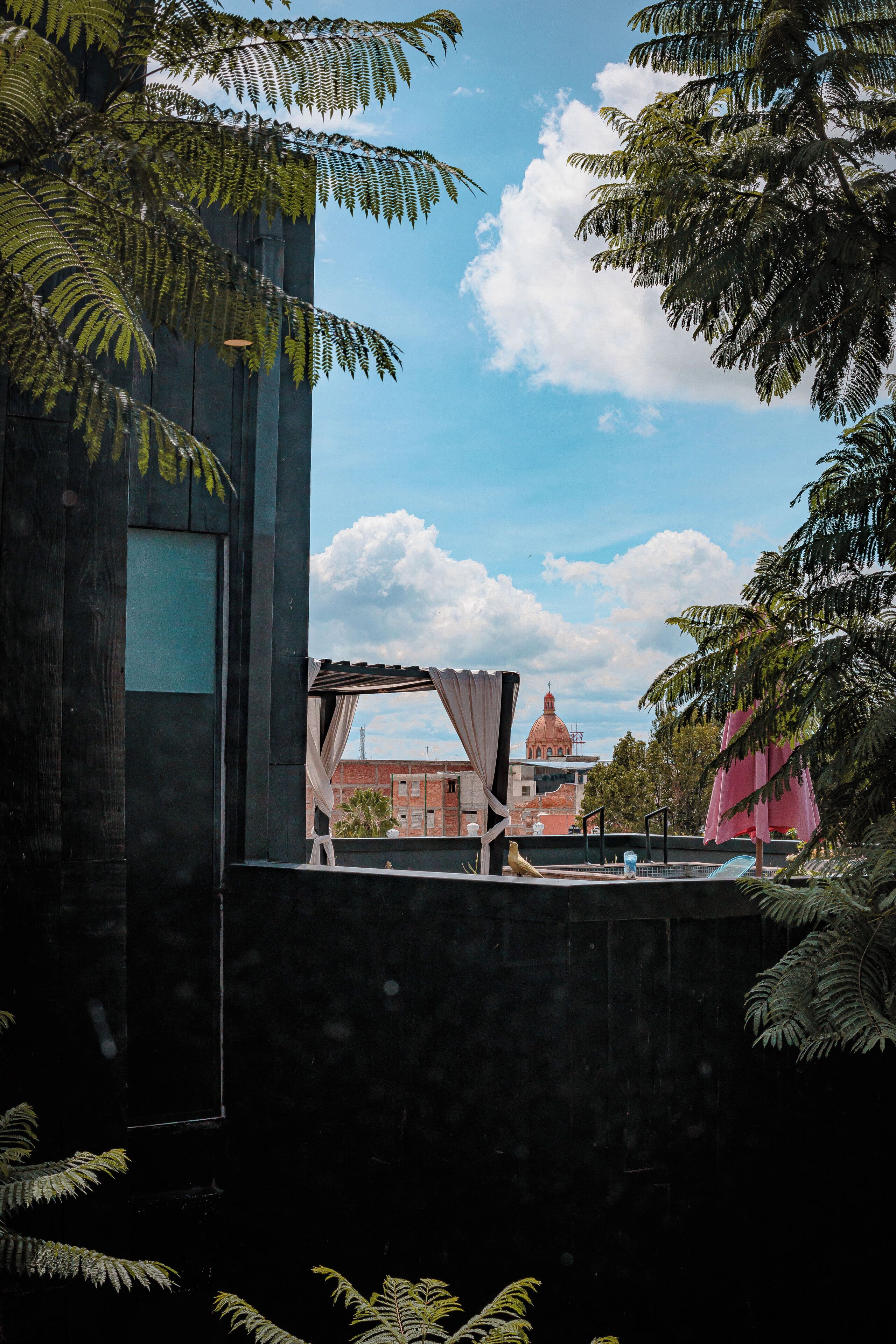 A modern building with a large window and a view of a red building with a dome in the background.