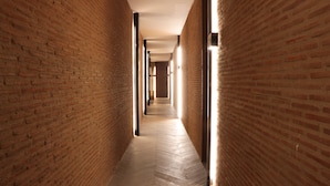 A corridor with brick walls and wooden flooring, leading to a distant room. - Elena de Cobre, Leon, a Member of Design Hotels (León)