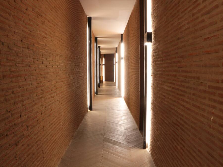 Un pasillo con paredes de ladrillo y suelo de madera, que conduce a una habitación distante.