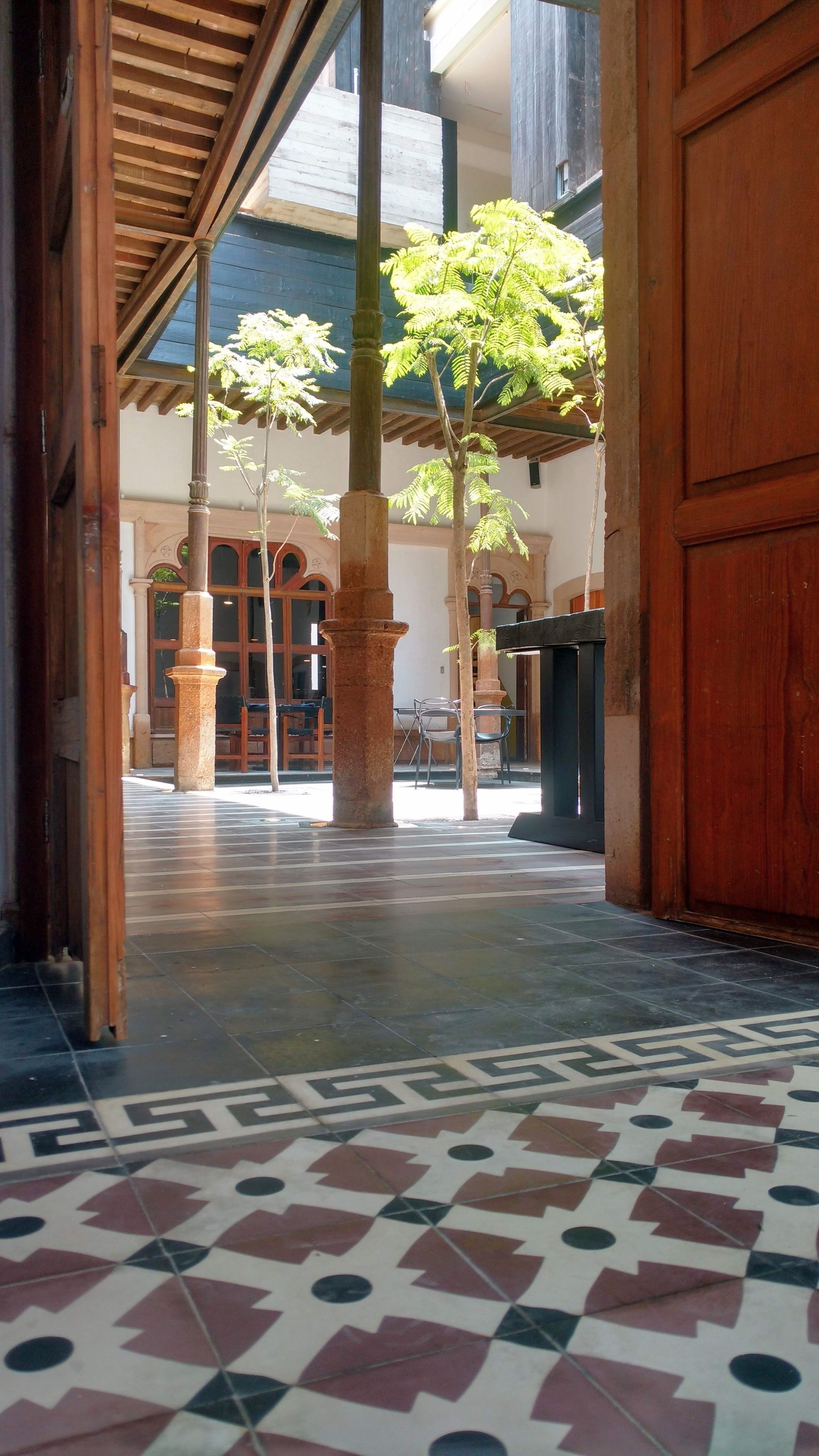 Un patio con suelo de baldosas, columnas de madera y una puerta.