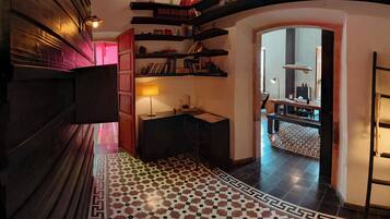 Un couloir avec un sol à carreaux, des étagères à livres, un bureau et une lampe.