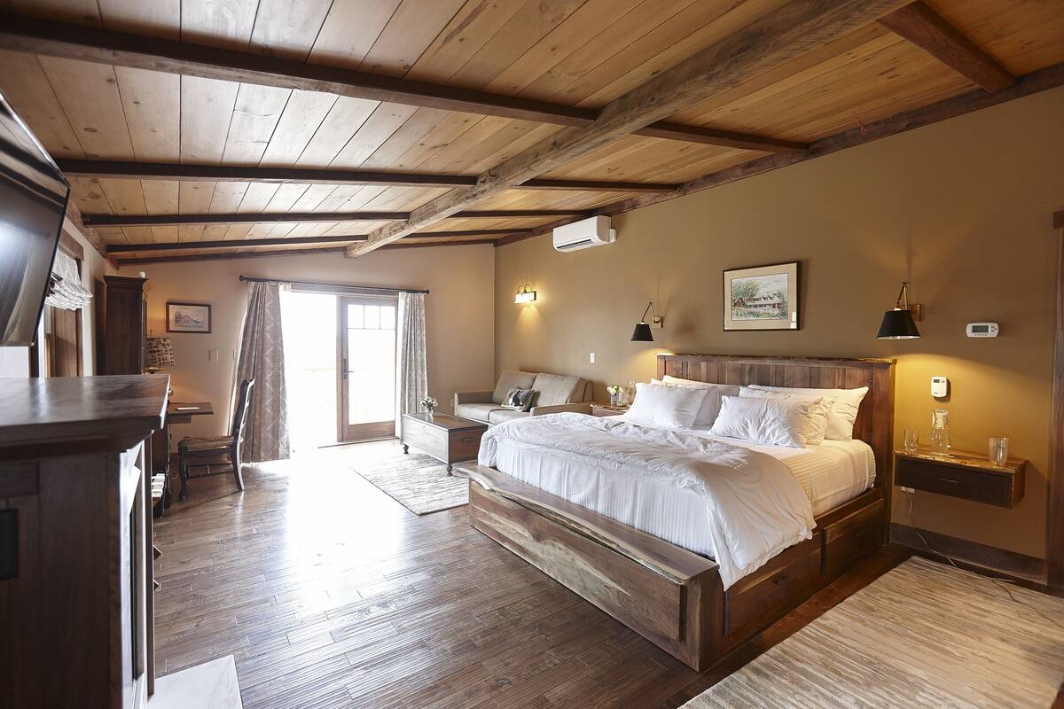 A bedroom with a wooden bed, bedside tables, a nightstand, a desk, and a chair.