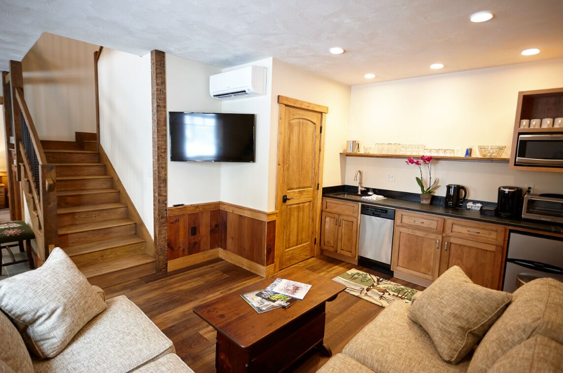 A modern kitchen with wooden cabinets, a built-in microwave, and a flat-screen TV.