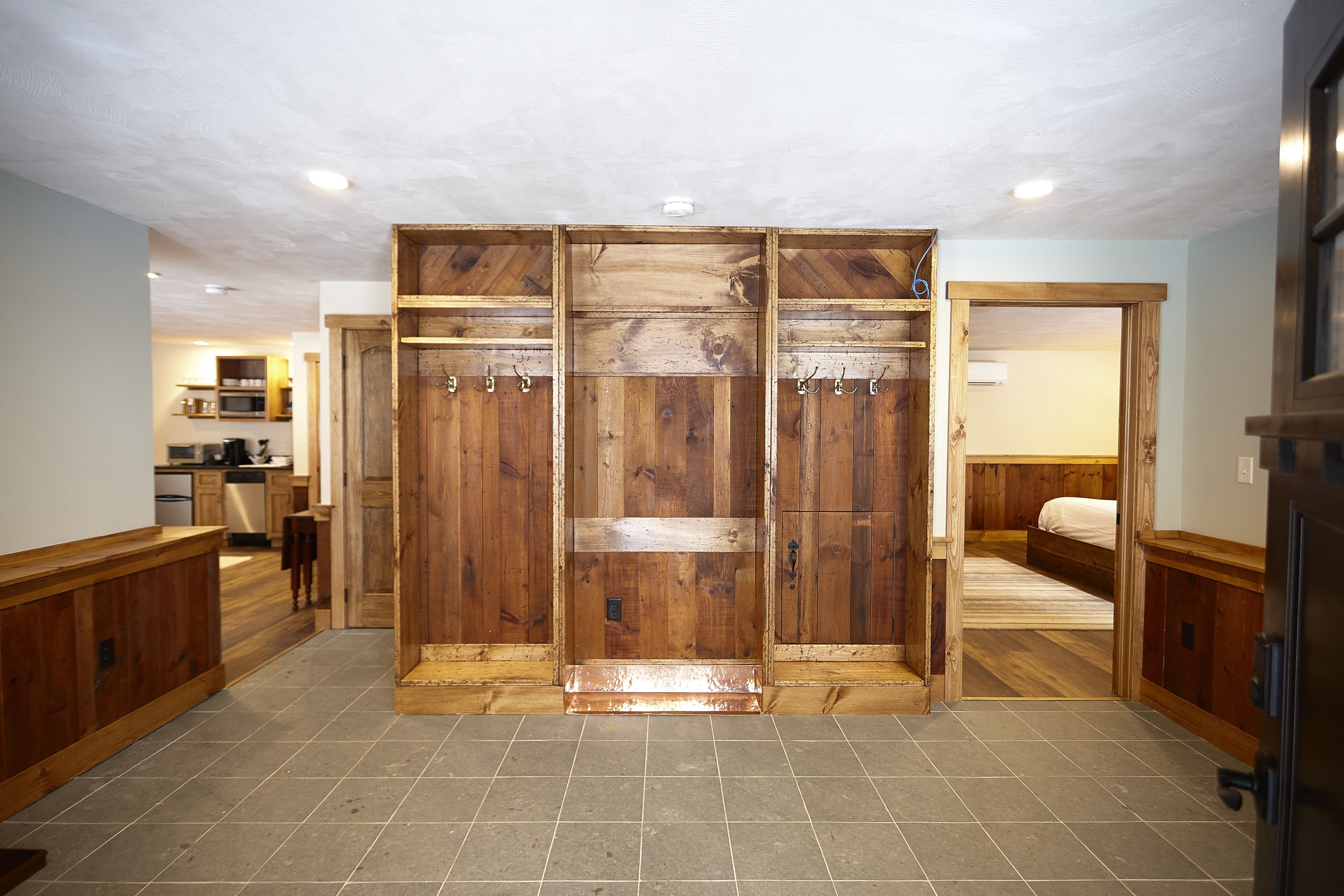 Une pièce spacieuse avec une grande armoire en bois, un lit et un coin cuisine visible au fond.
