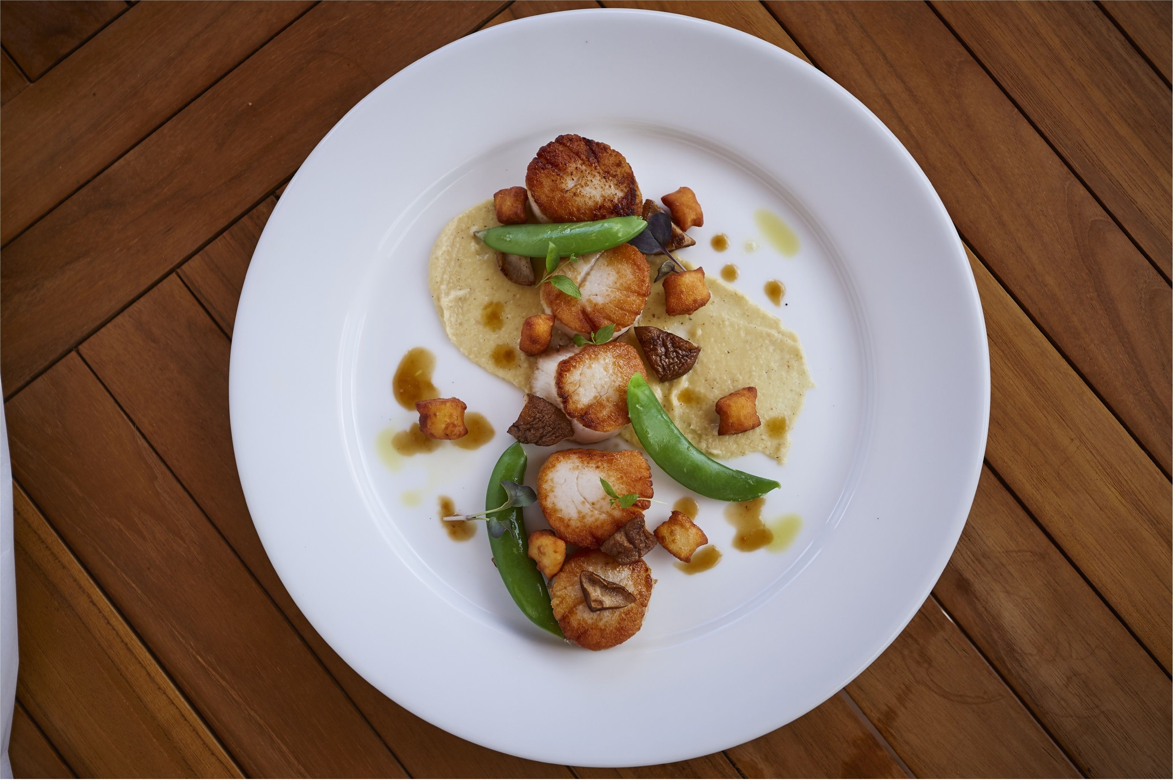 A white plate with food on a wooden table.