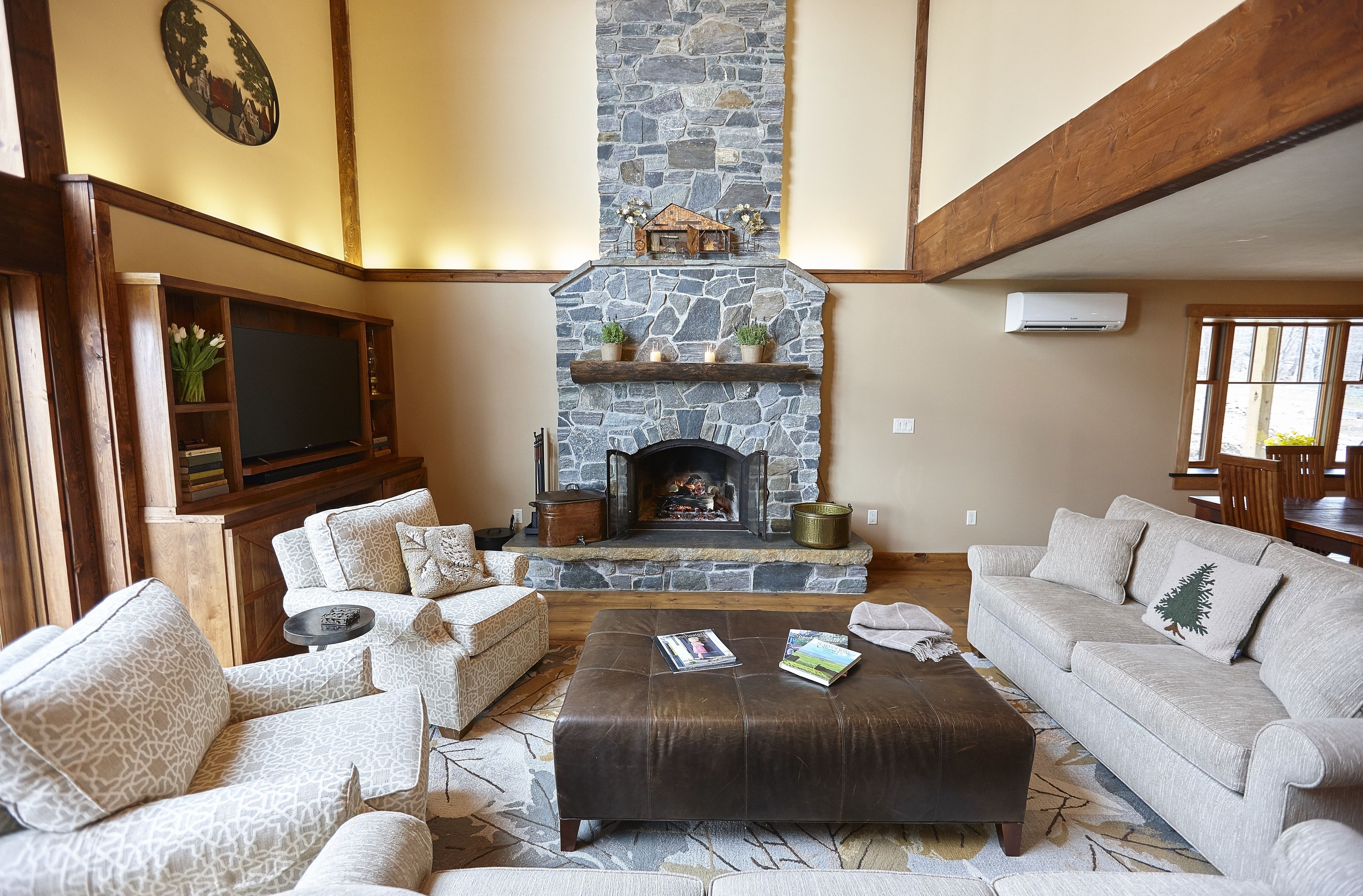 A cozy living room with a stone fireplace, comfortable seating, and a flat-screen TV.