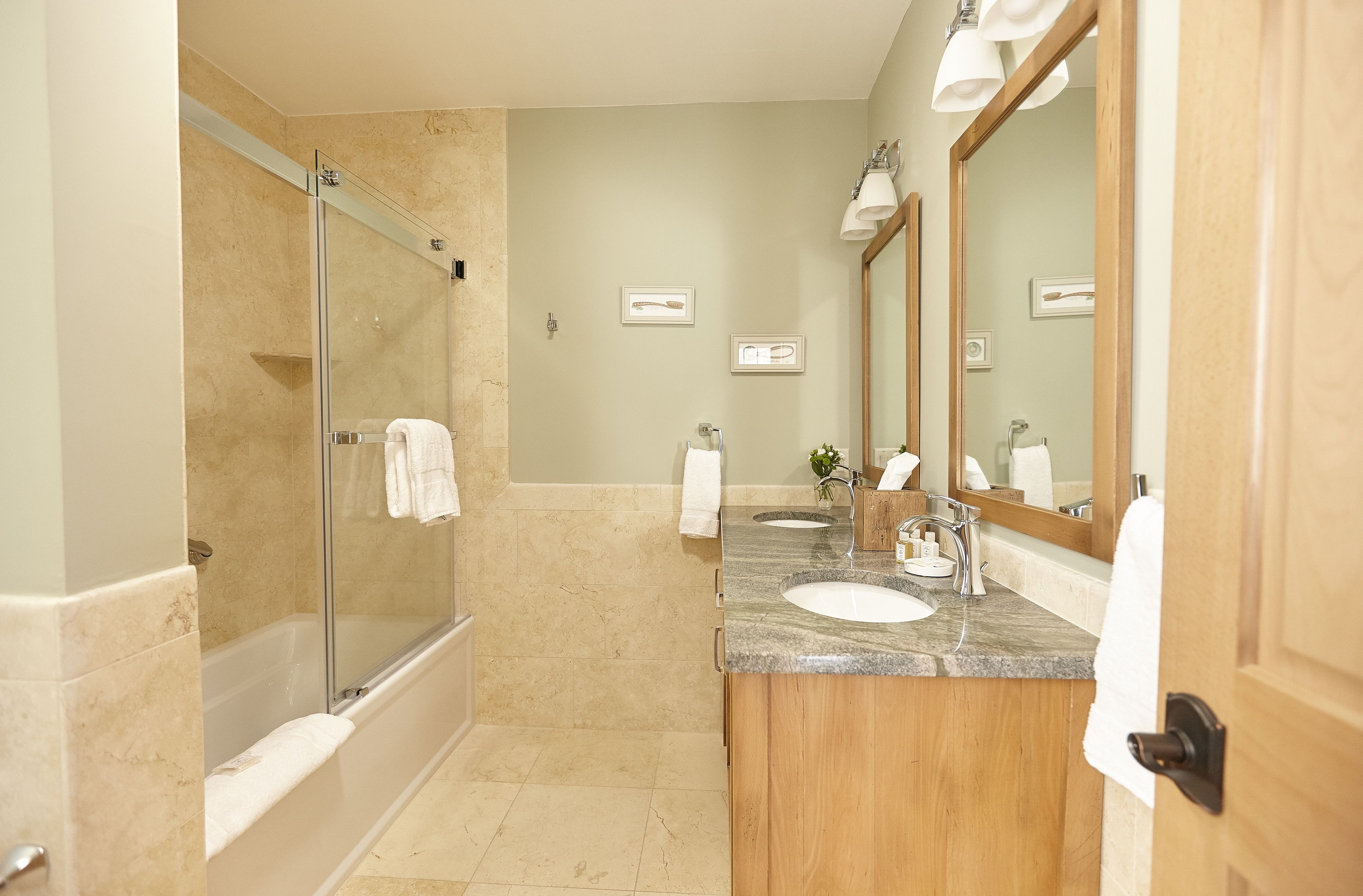 A modern bathroom with a glass-enclosed shower, two sinks, and a large mirror.