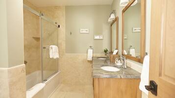 A modern bathroom with a glass-enclosed shower, two sinks, and a large mirror.