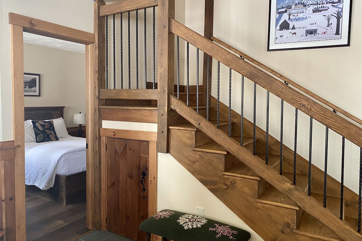 A wooden staircase with a handrail and a pet bed at the bottom.
