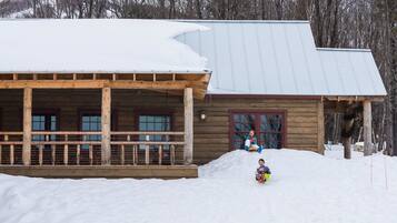 Situated in a serene winter landscape, this cabin features a cozy porch with a bench.