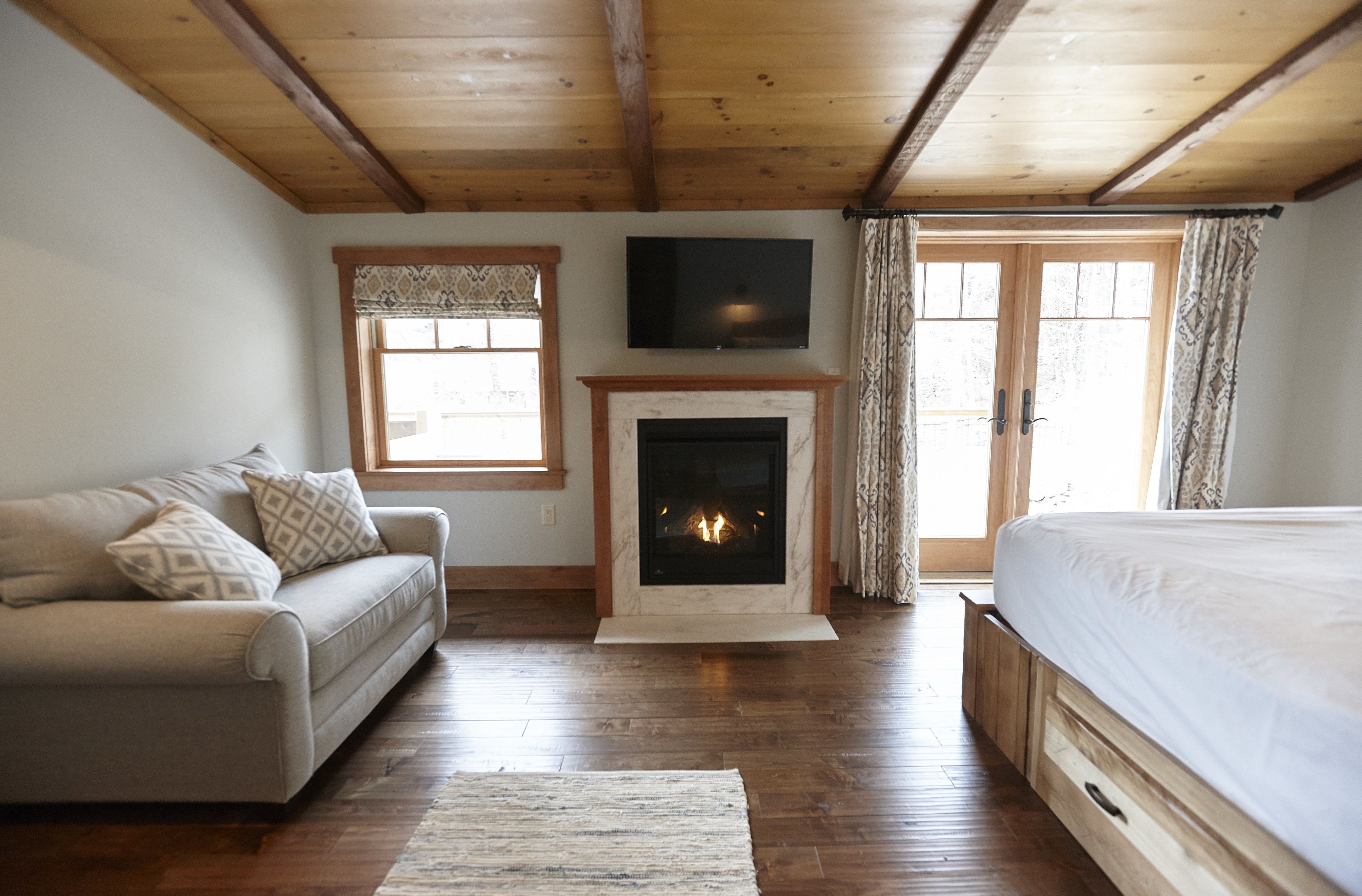 Un dormitorio con chimenea, sofá, cama y televisor en la pared.