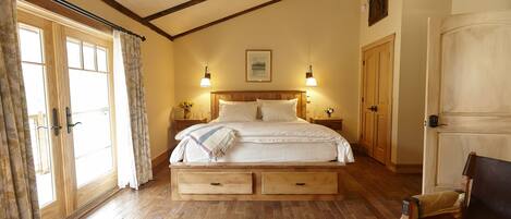 A bedroom with a wooden bed, two nightstands, a bench, and a wardrobe.