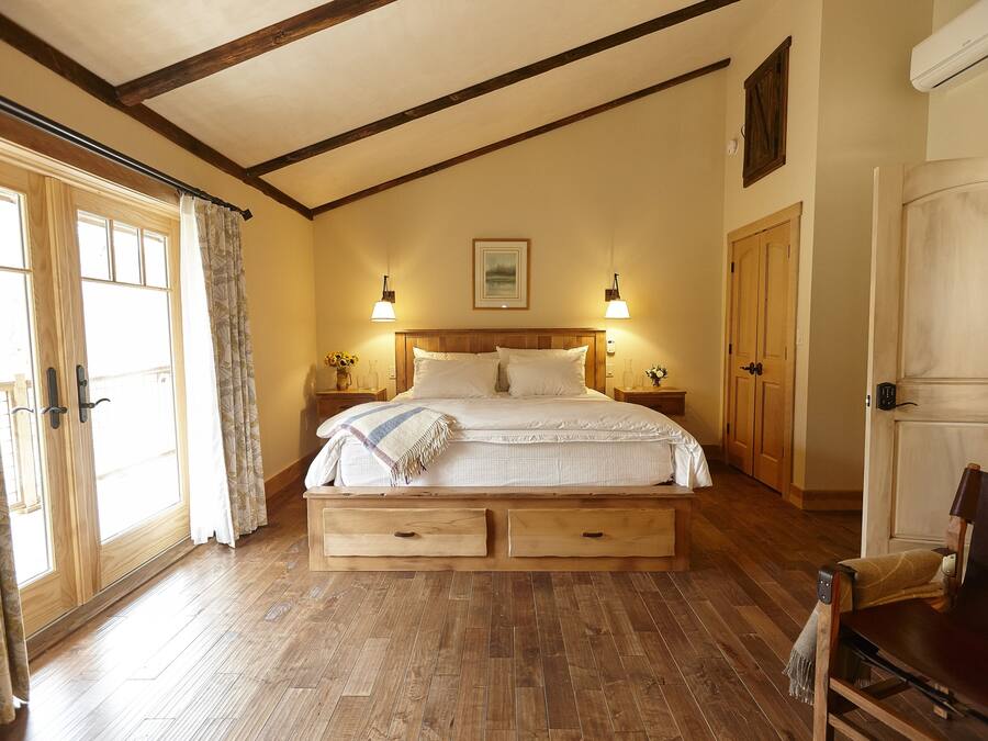 A bedroom with a wooden bed, two nightstands, a bench, and a wardrobe.