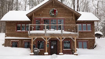 Une cabane en bois dotée d’un balcon, entourée de neige.