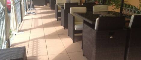 An outdoor patio area with wicker furniture, including sofas and tables, and a tiled floor.