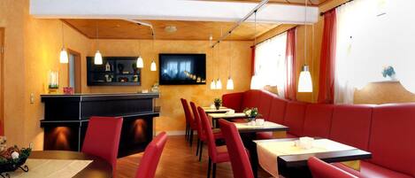 Un restaurante con asientos rojos, techo de madera y una zona de bar.