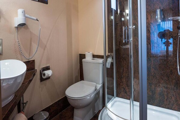 Un baño con lavamanos, inodoro y ducha envuelta en vidrio.