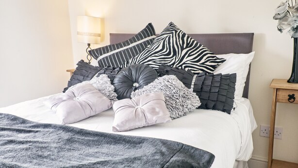 Un lit bien fait, agrémenté de plusieurs coussins et d’une couverture.