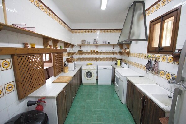 A compact kitchen with a washing machine, a stove, and a sink.