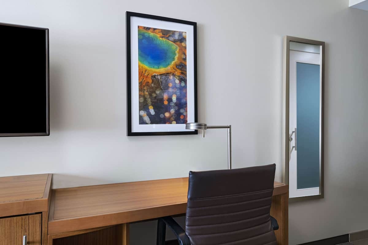 Ein moderner Arbeitsraum mit Schreibtisch, Stuhl, gerahmtem Kunstwerk und einer Tür.
