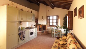 Una cocina con chimenea, un comedor con mesa y sillas, y un sofá.