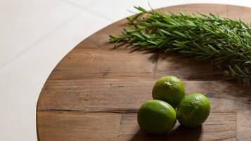 Una mesa de madera con tres limones verdes y una ramita de romero.