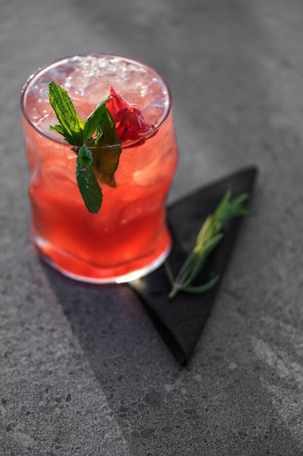 A cocktail glass with a rose and mint garnish on a dark surface. - Ikones Seafront Luxury Suites - Adults Only (Rethymno)