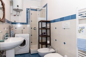 Ein Badezimmer mit Waschbecken, Waschmaschine, Bidet und einer Duschkabine.