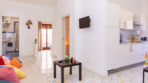 A modern apartment with a kitchen, dining area, and a living room with colorful cushions. - Residence Sorrento (Sorrento)