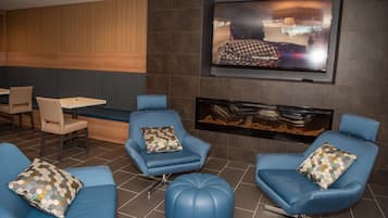 A modern lounge area with blue leather seating, a flat-screen TV mounted on the wall, and a fireplace.
