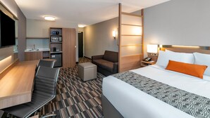 A hotel room with a bed, a desk, a sofa, a small table, and a kitchenette. - Microtel Inn & Suites by Wyndham Carlisle (Carlisle)