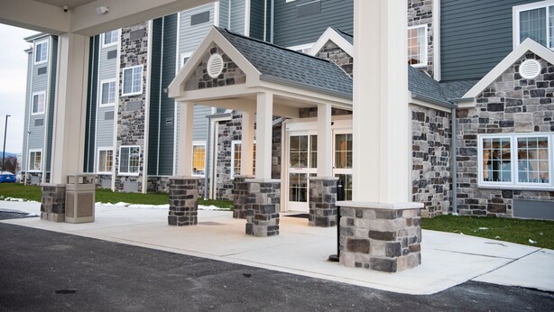 A building with a stone facade, a covered entrance, and a parking area. - Microtel Inn & Suites by Wyndham Carlisle (Carlisle)