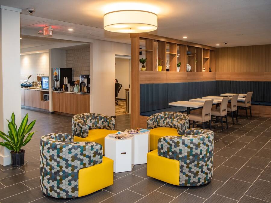 Un hall d’entrée moderne avec des espaces de détente, un comptoir d’accueil et un espace repas.
