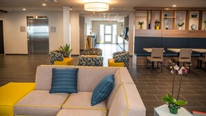 A modern lobby with a sofa, patterned chairs, a dining area, and a reception desk. - Microtel Inn & Suites by Wyndham Carlisle (Carlisle)