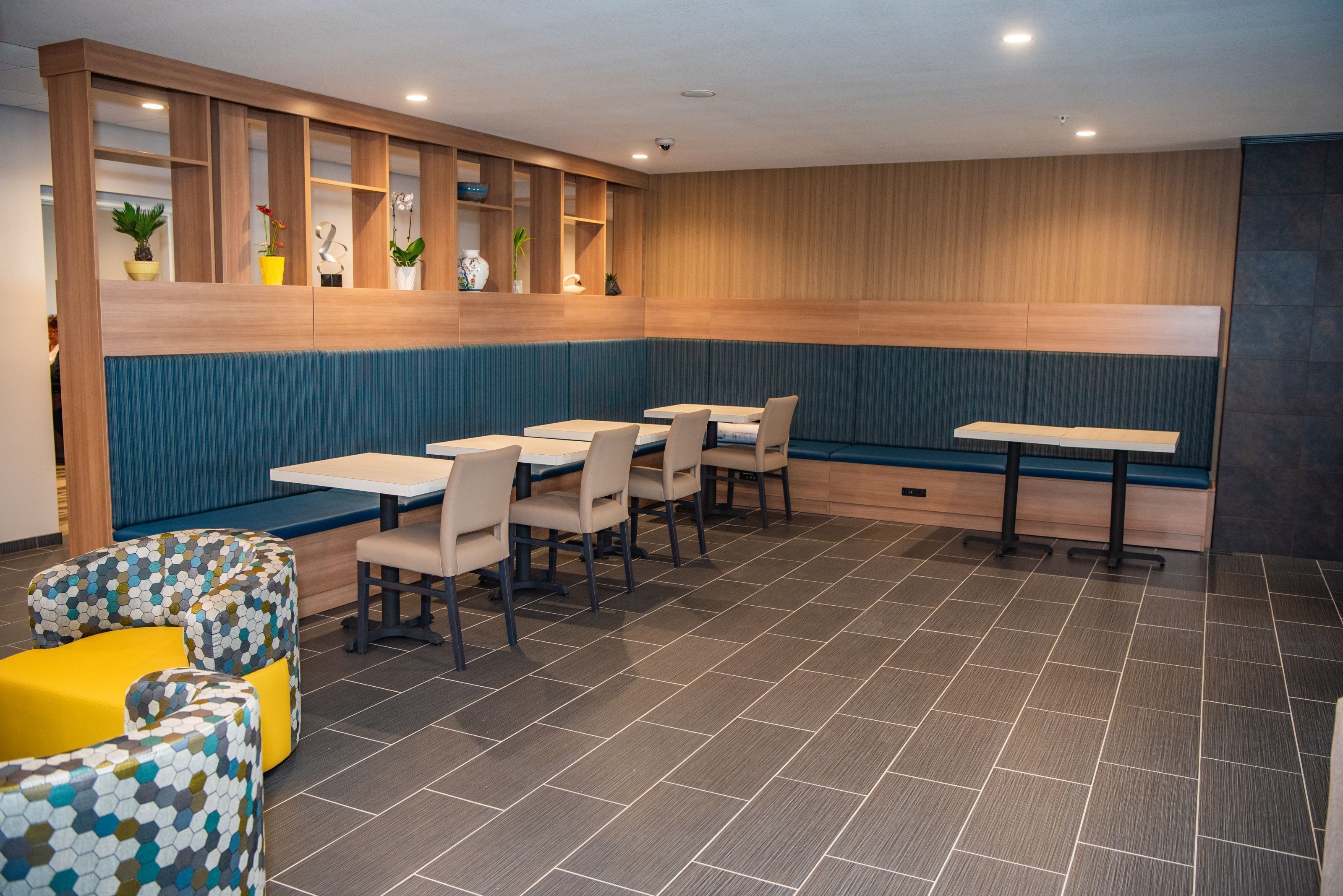 A modern restaurant with wooden paneling, blue cushioned seating, and multiple tables.