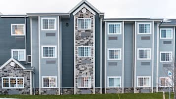 Un edificio residencial de varios pisos con fachada de piedra y diseño de ventanas uniforme.
