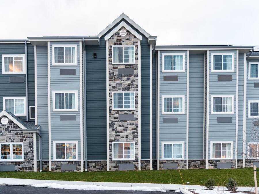 Un edificio residencial de varios pisos con fachada de piedra y diseño de ventanas uniforme.