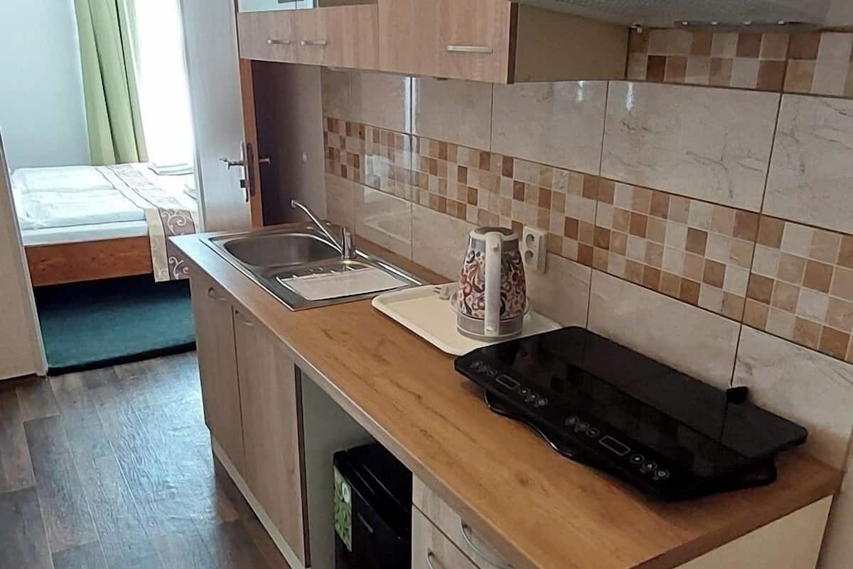 Una cocina compacta con armarios de madera, microondas, tetera y lavavajillas.