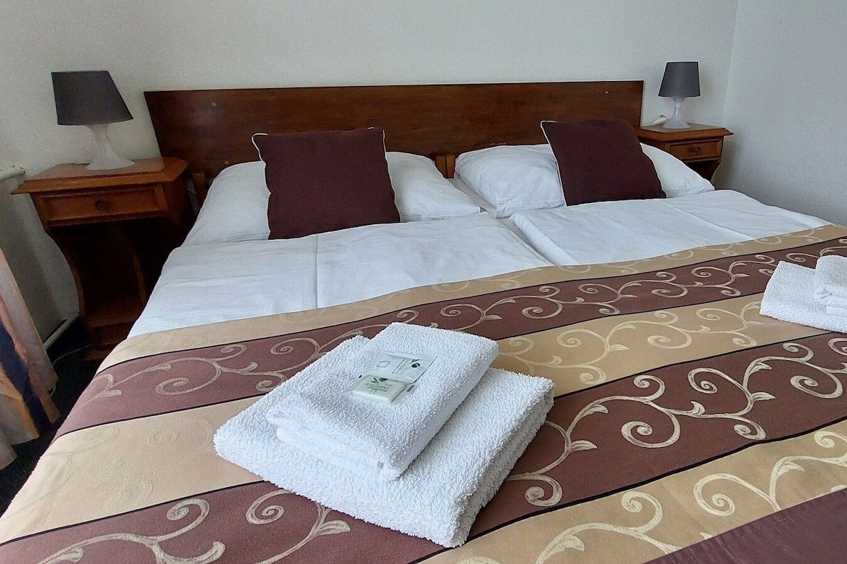 A hotel room with a large bed, two bedside tables, and a headboard.