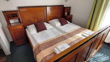 A hotel room with a wooden bed, two bedside tables, and a window with curtains.