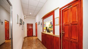 A hallway with a reception desk, framed pictures on the walls, and a tiled floor.