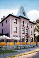 Un edificio rosa con un letrero que dice "Grand Hotel" y una pared de piedra con vallas amarillas.