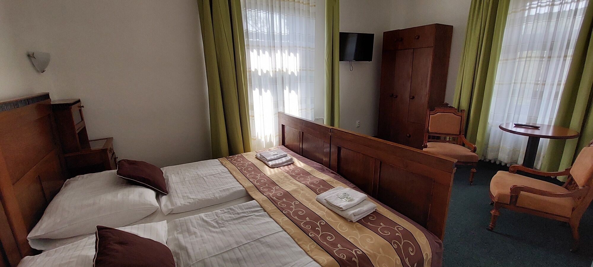 Una habitación de hotel con una cama, un armario de madera, una mesita y una silla.
